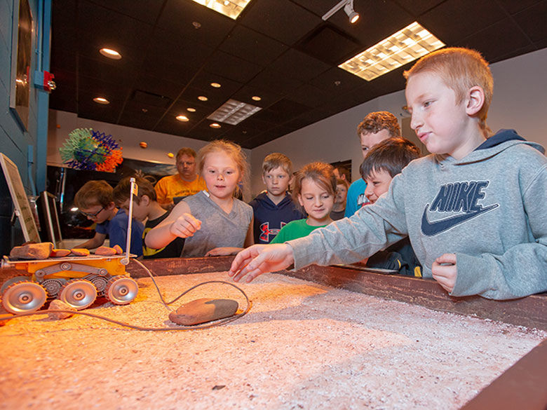 A group of children plays with a Mars rover model at Yahn Planetarium.